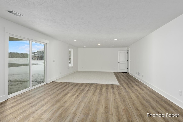 unfurnished living room with baseboards, recessed lighting, a textured ceiling, visible vents, and wood finished floors