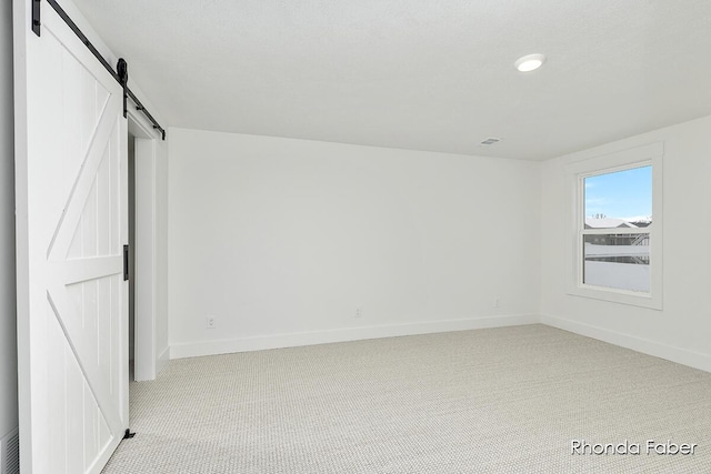 unfurnished bedroom featuring visible vents, baseboards, carpet, and a barn door