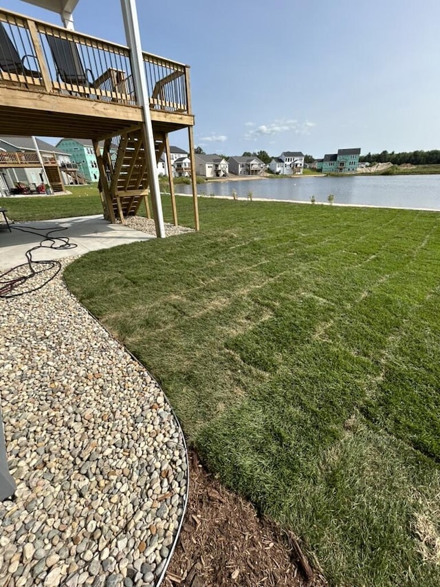 view of yard featuring a patio area, a deck with water view, and stairs