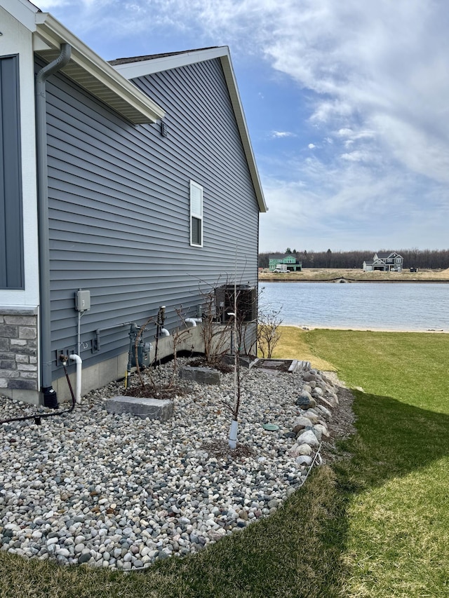 view of home's exterior with a water view and a lawn