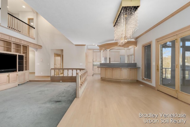 7635 Sandy Hollow Dr SE, Alto, MI 49302 - kitchen featuring built in shelves, light wood-style flooring, a towering ceiling, ornamental molding, and a chandelier