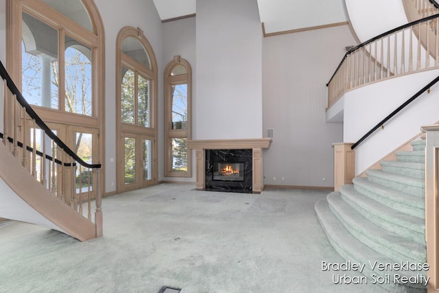 7635 Sandy Hollow Dr SE, Alto, MI 49302 - unfurnished living room with a high ceiling, carpet floors, stairs, a fireplace, and baseboards