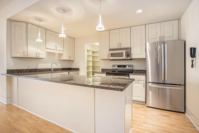20 Hiawatha Dr, Battle Creek, MI 49015 - kitchen with stainless steel appliances, light wood-style floors, dark stone countertops, and decorative light fixtures