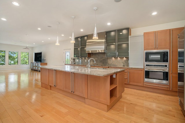 20 Hiawatha Dr, Battle Creek, MI 49015 - kitchen with stainless steel oven, wall chimney exhaust hood, black microwave, tasteful backsplash, and light wood-type flooring