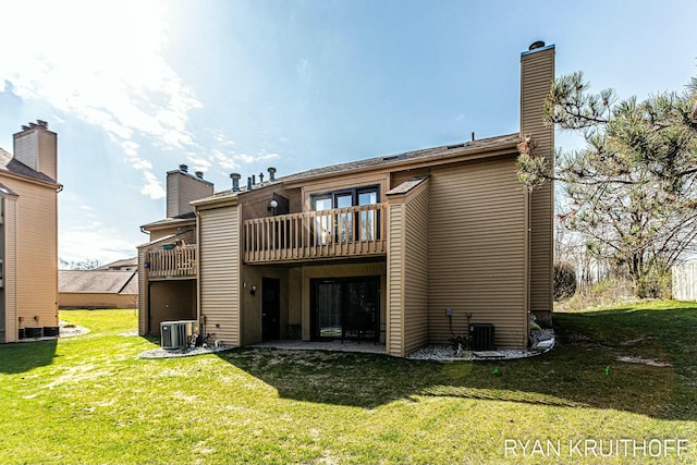back of house featuring central air condition unit, a chimney, a yard, and a balcony