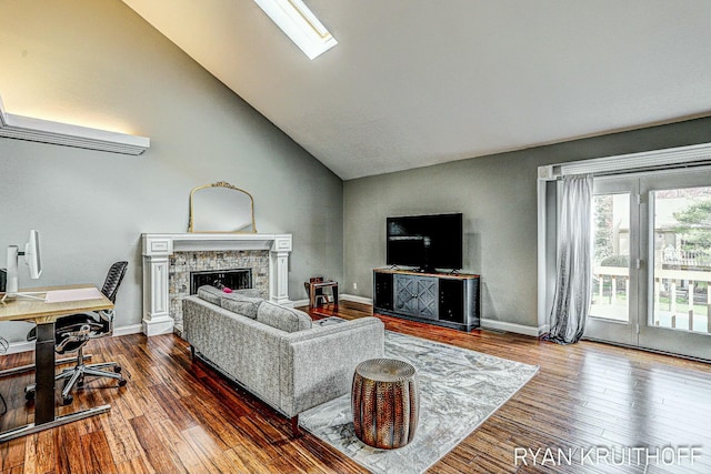 living room featuring a fireplace, vaulted ceiling, and wood finished floors