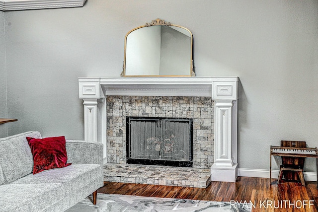 interior details with a stone fireplace, baseboards, and wood finished floors