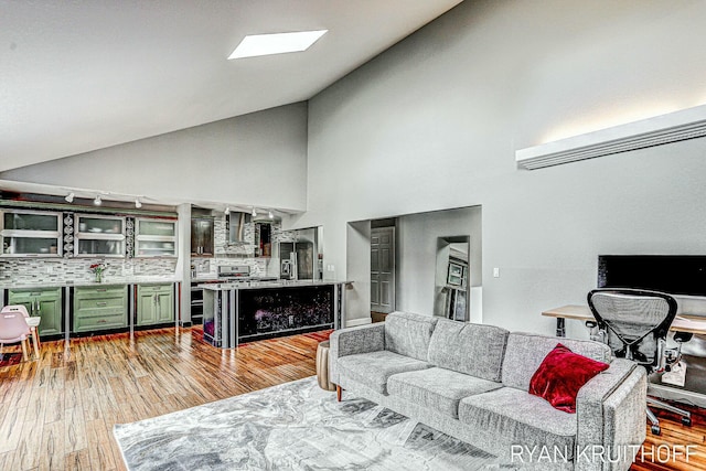 living area featuring light wood finished floors and high vaulted ceiling
