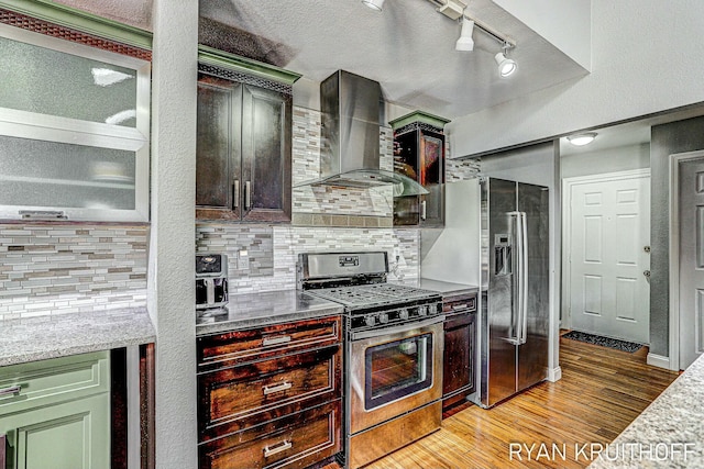 kitchen with stainless steel appliances, light wood-style flooring, backsplash, and wall chimney range hood