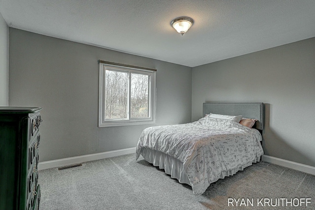 carpeted bedroom with a textured ceiling, visible vents, and baseboards