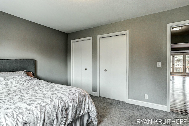 carpeted bedroom featuring multiple closets and baseboards