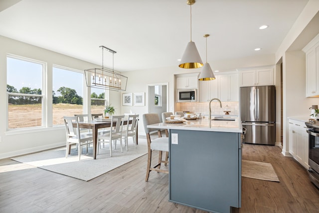 8167 Turning Stone, Kalamazoo, MI 49009 - kitchen with appliances with stainless steel finishes, tasteful backsplash, white cabinets, wood finished floors, and a center island with sink