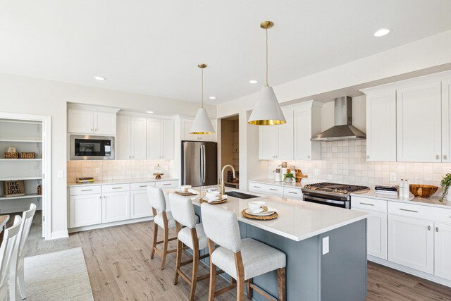 8167 Turning Stone, Kalamazoo, MI 49009 - kitchen featuring wall chimney range hood, stainless steel appliances, backsplash, a kitchen bar, and an island with sink