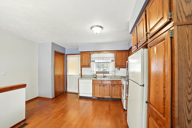 256 Bona Vista Dr NW, Grand Rapids, MI 49504 - kitchen with brown cabinetry, white appliances, a sink, and dark wood-style flooring
