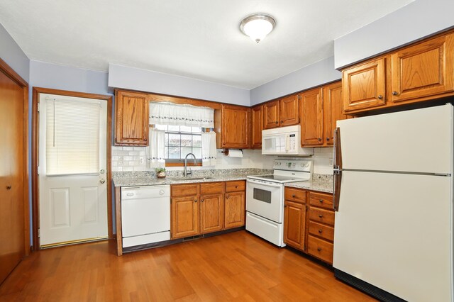 256 Bona Vista Dr NW, Grand Rapids, MI 49504 - kitchen with brown cabinetry, wood finished floors, white appliances, and a sink