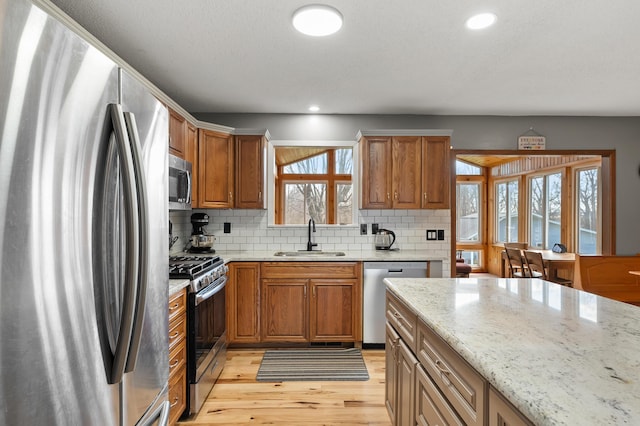 8524 E B Ave, Richland, MI 49083 - kitchen with appliances with stainless steel finishes, a sink, light wood finished floors, backsplash, and light stone countertops