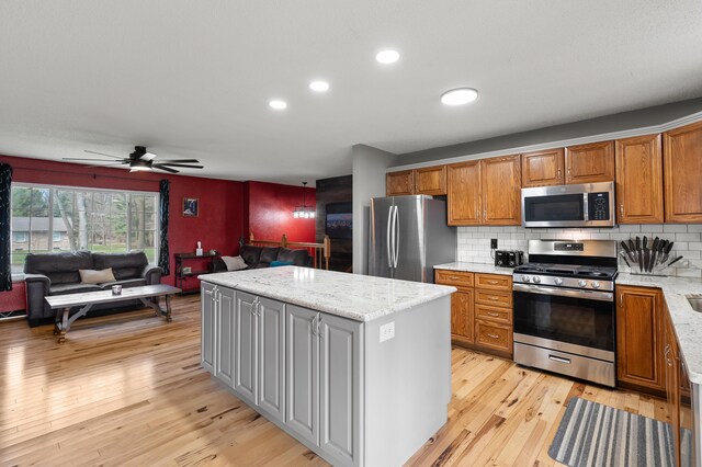 8524 E B Ave, Richland, MI 49083 - kitchen with stainless steel appliances, a kitchen island, open floor plan, light wood-type flooring, and brown cabinetry