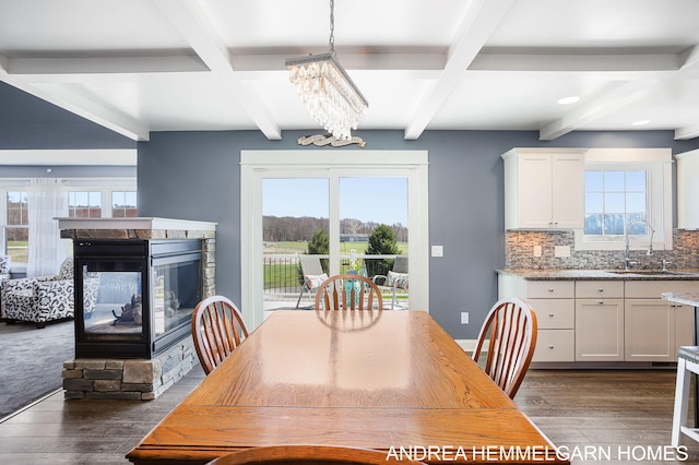 4459 36th St, Hamilton, MI 49419 - dining space with beamed ceiling, dark wood-style floors, an inviting chandelier, and a multi sided fireplace
