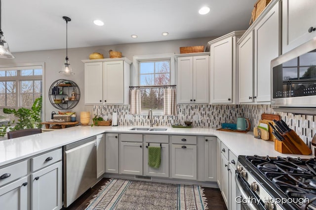 kitchen featuring tasteful backsplash, stainless steel appliances, light countertops, and a sink