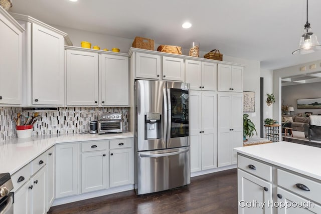 kitchen featuring light countertops, dark wood-type flooring, stainless steel fridge, tasteful backsplash, and hanging light fixtures