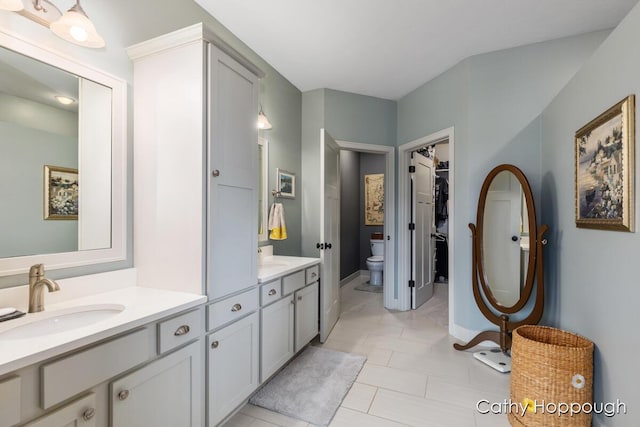 bathroom featuring tile patterned floors, toilet, baseboards, a spacious closet, and vanity