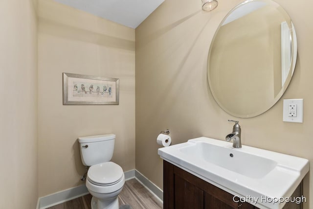 bathroom with baseboards, wood finished floors, vanity, and toilet