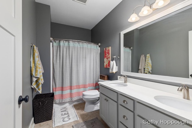 full bath with a sink, double vanity, and toilet