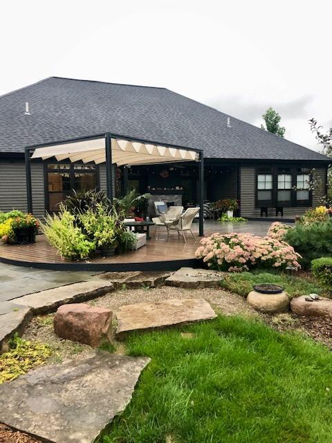 back of house featuring roof with shingles, a patio, and a deck