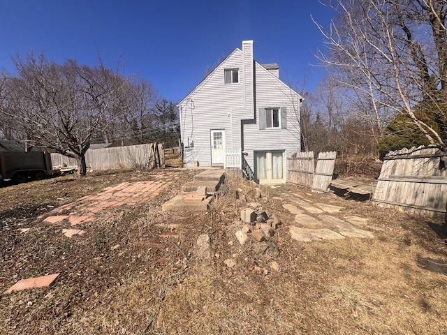 rear view of house featuring fence and a chimney