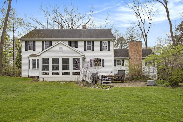 back of property with a lawn, a chimney, a patio area, and a sunroom