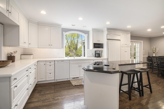 kitchen featuring crown molding, a kitchen breakfast bar, black appliances, and plenty of natural light