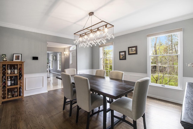 dining space featuring an inviting chandelier, a wainscoted wall, and crown molding