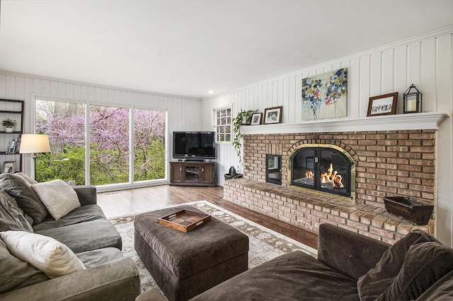 living area featuring a brick fireplace, a wealth of natural light, and wood finished floors