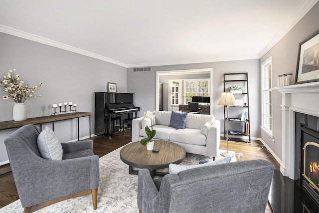 living room featuring a lit fireplace, ornamental molding, a wealth of natural light, and visible vents