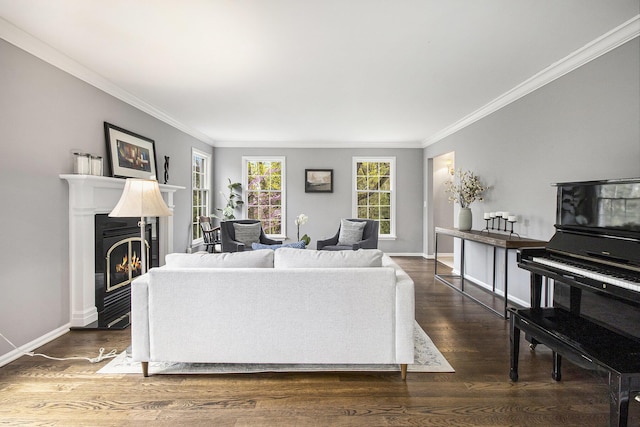 living room featuring baseboards, ornamental molding, a glass covered fireplace, and wood finished floors