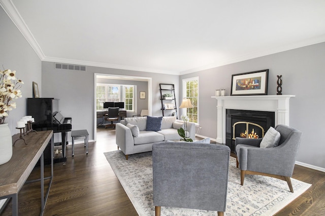 living room with visible vents, crown molding, baseboards, a warm lit fireplace, and dark wood finished floors