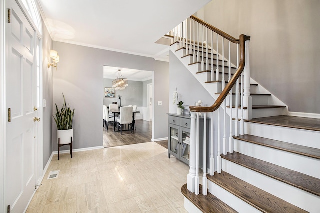 foyer entrance with stairs, baseboards, visible vents, and ornamental molding