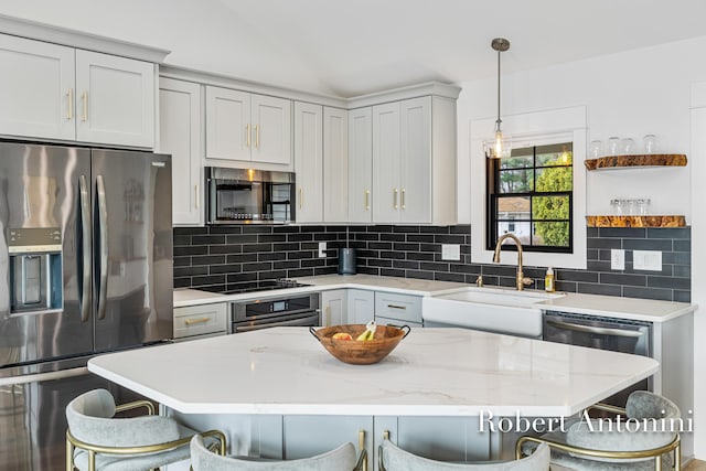 2301 Schimperle Dr NE, Grand Rapids, MI 49525 - kitchen with stainless steel appliances, a sink, a breakfast bar, tasteful backsplash, and hanging light fixtures
