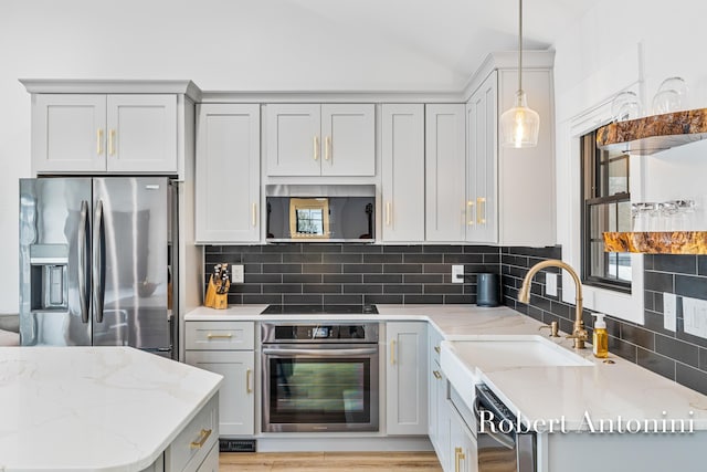 2301 Schimperle Dr NE, Grand Rapids, MI 49525 - kitchen featuring appliances with stainless steel finishes, tasteful backsplash, gray cabinetry, hanging light fixtures, and lofted ceiling