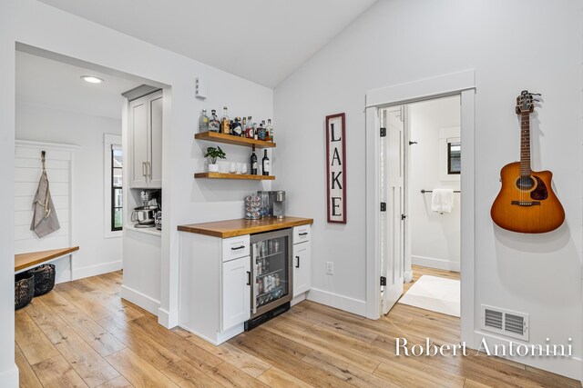 2301 Schimperle Dr NE, Grand Rapids, MI 49525 - indoor dry bar featuring beverage cooler, light wood finished floors, lofted ceiling, recessed lighting, and baseboards