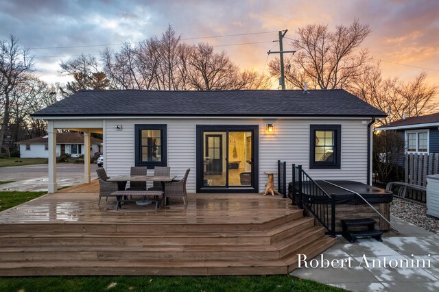 2301 Schimperle Dr NE, Grand Rapids, MI 49525 - back of house at dusk with a wooden deck, outdoor dining area, and roof with shingles
