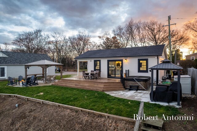 2301 Schimperle Dr NE, Grand Rapids, MI 49525 - back of property at dusk with a gazebo, a hot tub, a deck, and a patio
