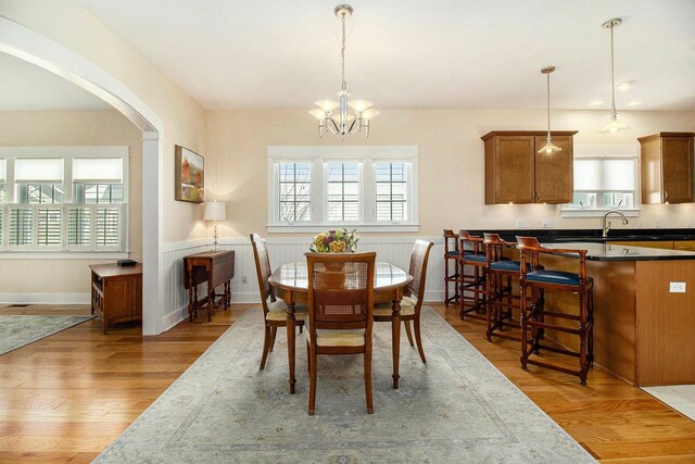 8 Georgia Ct, Pentwater, MI 49449 - dining room with arched walkways, a notable chandelier, plenty of natural light, and light wood-type flooring