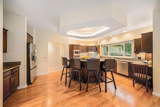 2925 Exmoor Rd, Ann Arbor, MI 48104 - kitchen featuring stainless steel appliances, a breakfast bar, light wood-style flooring, a tray ceiling, and a kitchen island