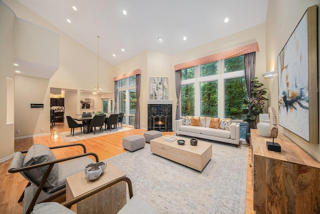 2925 Exmoor Rd, Ann Arbor, MI 48104 - living area with light wood-style flooring, a warm lit fireplace, high vaulted ceiling, and recessed lighting
