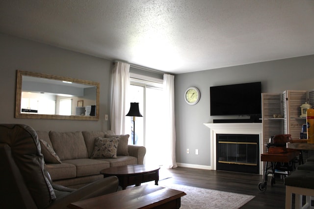 3184 Windcrest Dr # 14, Grand Rapids, MI 49525 - living area featuring dark wood-style floors, a textured ceiling, baseboards, and a glass covered fireplace