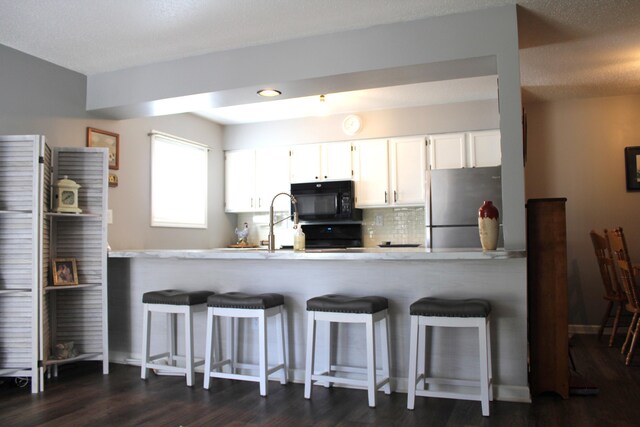 3184 Windcrest Dr # 14, Grand Rapids, MI 49525 - kitchen featuring dark wood-type flooring, black microwave, freestanding refrigerator, and a peninsula