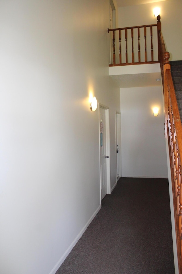 3184 Windcrest Dr # 14, Grand Rapids, MI 49525 - corridor with dark colored carpet, stairway, a towering ceiling, and baseboards