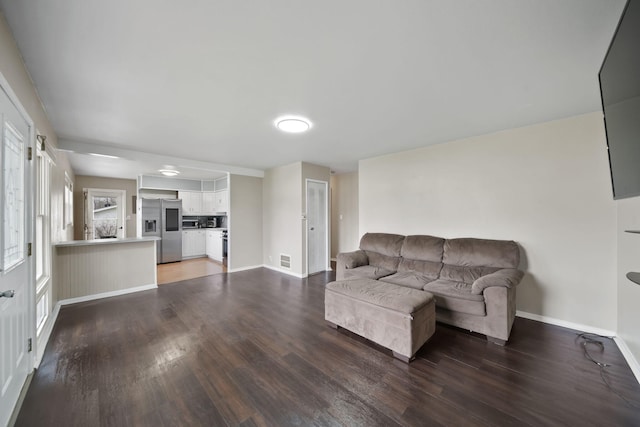 living room with visible vents, baseboards, and wood finished floors