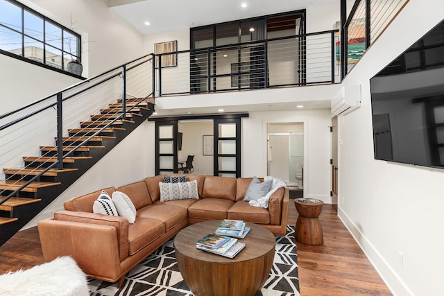 22 Jefferson Ave SE, Grand Rapids, MI 49503 - living room featuring a towering ceiling, a wall mounted air conditioner, wood finished floors, baseboards, and stairway